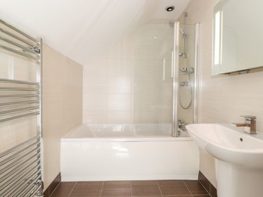A bathroom with a bathtub shower combination sink and towel rail at Latrigg House in Keswick