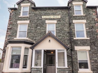 A stone house with multiple windows and a porch entrance with a sign that reads Latrigg House in Keswick