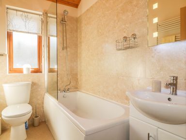 A bathroom with a bathtub shower toilet sink and window at Holmedell in Greystoke