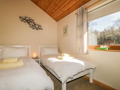 A bedroom with two single beds with white bedding and folded towels on each bed at Holmedell in Greystoke