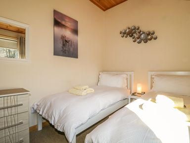 A bedroom with two single beds, a chest of drawers, wall art, and folded towels at Holmedell in Greystoke
