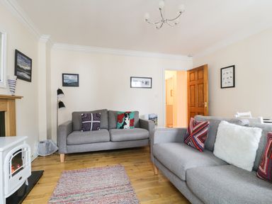 A living room with two grey sofas and colorful cushions a rug and a white heater at Siskin in Keswick