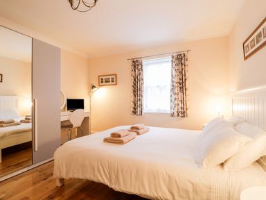 A bedroom with a bed towels on it a desk and chair with a small television and a wardrobe with mirrored doors at Siskin in Keswick