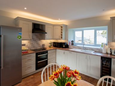 A kitchen with cabinets oven stove refrigerator and flowers on a table at Westmains Farm in Penton
