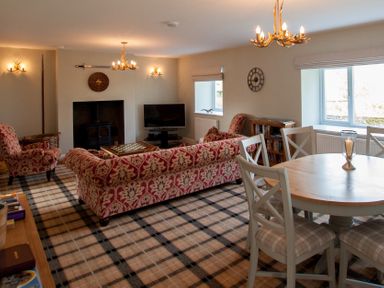 A living room with patterned sofas a round dining table and a fireplace at Westmains Farm in Penton