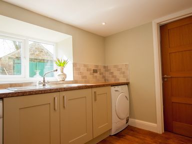 A utility room with a washing machine under the counter and a vase on the windowsill at Westmains Farm in Penton