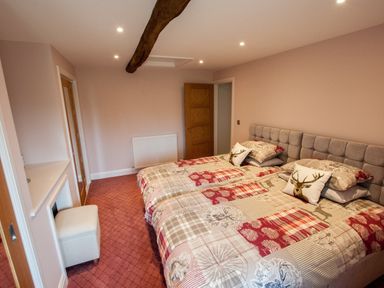 A bedroom with two single beds pushed together with patterned bedding and deer cushions at Westmains Farm in Penton