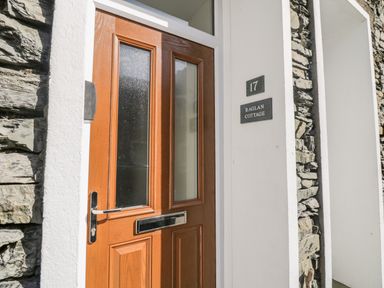 A wooden front door with glass panels and a letterbox at 17 Raglan Cottage in Bowness-on-Windermere