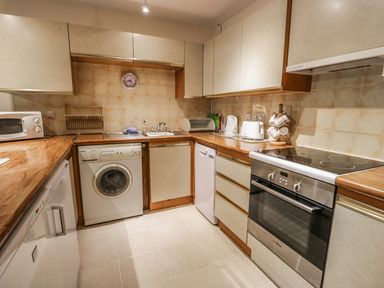 A kitchen with washing machine microwave toaster oven and cabinets at Treetops in Windermere