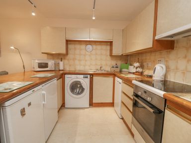 A kitchen with washing machine microwave oven and kettle at Treetops in Windermere