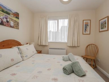 A bedroom with a double bed and two rolled towels on the bed at Treetops in Windermere