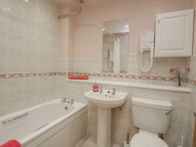 A bathroom with a bathtub toilet sink and mirror at Treetops in Windermere