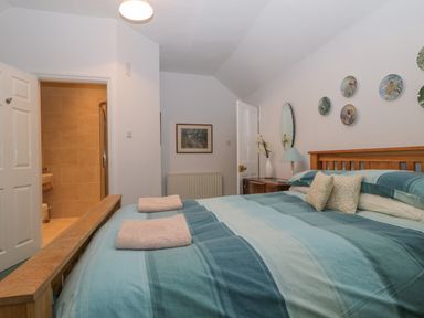 A bedroom with a wooden bed and blue bedding with folded towels and wall decorations at The Old Vicarage in Keswick