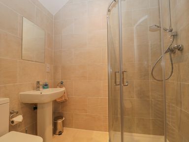 A bathroom with a toilet sink mirror and a glass shower at The Old Vicarage in Keswick