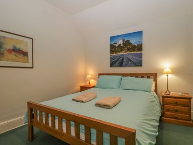 A bedroom with a wooden bed and two bedside tables with lamps at The Old Vicarage in Keswick