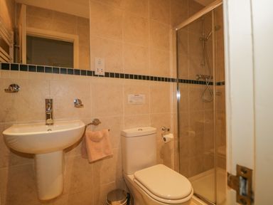 A bathroom with a sink, toilet, towel rack, and shower at The Old Vicarage in Keswick