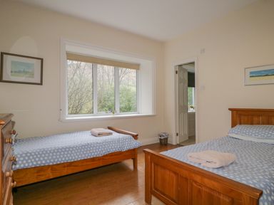 A bedroom with two single wooden beds with polka dot bedding a chest of drawers and a window at The Old Vicarage in Keswick