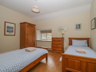 A bedroom with two single beds wooden furniture and a window at The Old Vicarage in Keswick
