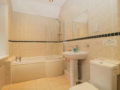 A bathroom with a bathtub shower combination a sink and a toilet at The Old Vicarage in Keswick