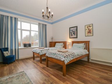 A bedroom with two single beds wooden furniture and striped curtains at The Old Vicarage in Keswick
