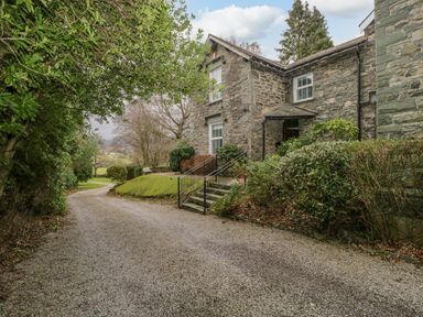 A stone house with stairs and greenery along a gravel driveway at The Old Vicarage in Keswick