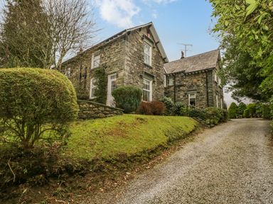 A stone house with a gravel driveway and trimmed bushes at The Old Vicarage in Keswick