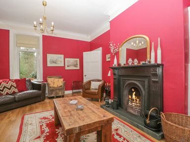 A living room with red walls a wooden coffee table and a fireplace at The Old Vicarage in Keswick