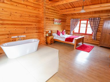 A bedroom with a bed pillows and a bathtub on a tiled area at Ash Lodge in Greetham Rutland