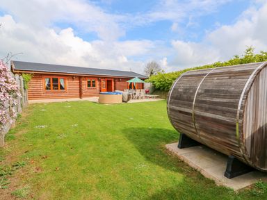 A backyard with a wooden log cabin patio furniture and a wooden barrel sauna at Yew Lodge in Greetham Rutland