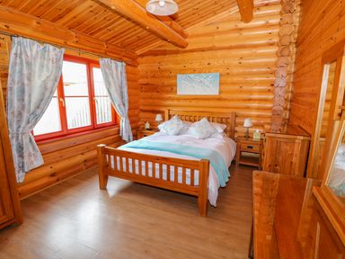 A bedroom with wooden bed and furniture and curtains on window at Yew Lodge in Greetham Rutland