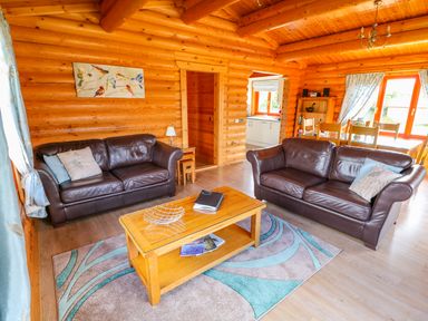 A living room with two brown leather sofas a wooden coffee table and a dining area at Yew Lodge in Greetham Rutland