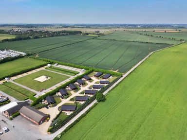 A rural area with multiple small buildings and caravans surrounded by green fields at Yew Lodge in Greetham Rutland