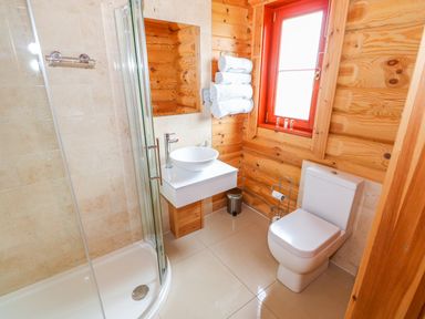 A bathroom with a shower enclosure toilet sink mirror and a window at Willow Lodge in Greetham Rutland