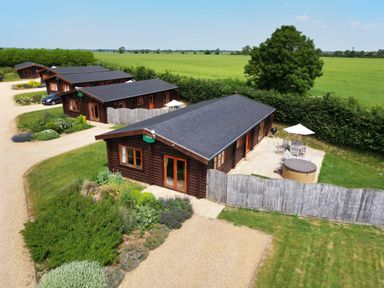A row of wooden lodges with patios and garden furniture in a rural setting at Willow Lodge in Greetham Rutland