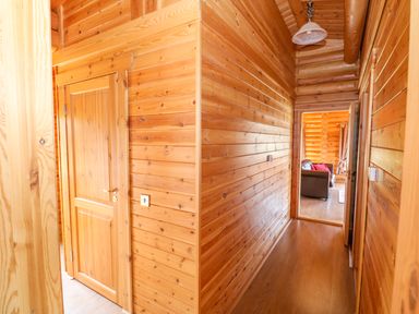 A wooden hallway with doors and a view into a room with a sofa at Sycamore Lodge in Greetham Rutland
