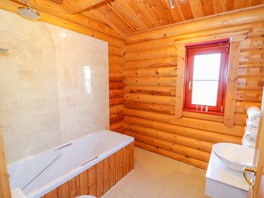 A bathroom with a bathtub shower toilet window and basin at Sycamore Lodge in Greetham Rutland