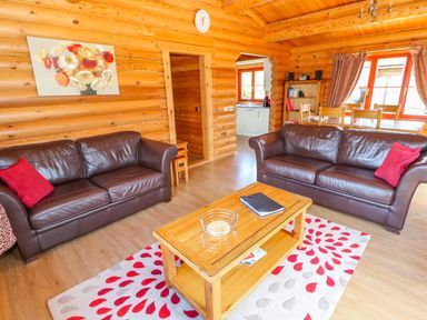 A living room with two brown leather sofas red cushions wooden coffee table and floral rug at Sycamore Lodge in Greetham Rutland