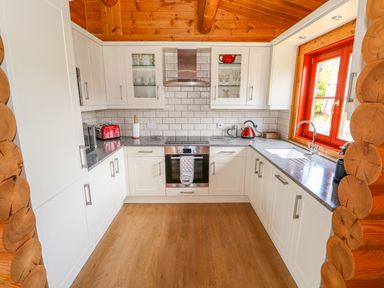 A kitchen with white cabinets a red toaster a kettle a sink and a window at Sycamore Lodge in Greetham Rutland