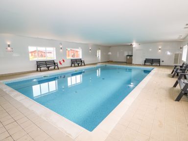 An indoor swimming pool with benches along the walls and windows at Church View in Greetham Rutland
