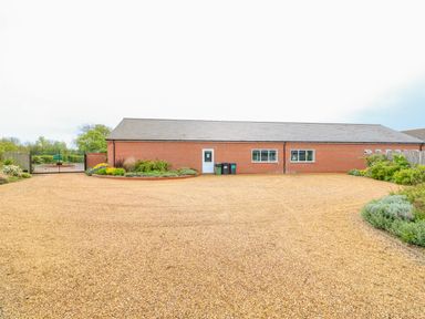 A driveway with gravel in front of a brick building with two windows and a door at Church View in Greetham Rutland