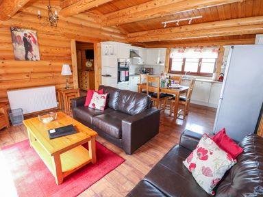 A living room and kitchen area with brown leather sofas and wooden dining table at Church View in Greetham Rutland