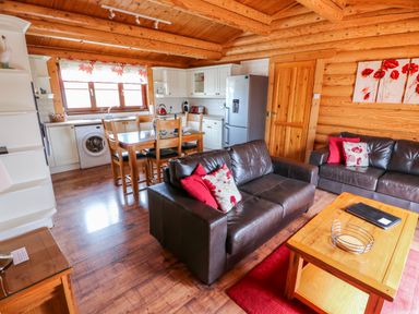A living room and kitchen with wooden furniture and leather sofas at Church View in Greetham Rutland