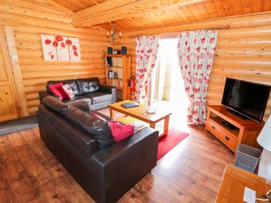 A living room with leather sofas wooden furniture and floral curtains at Church View in Greetham Rutland
