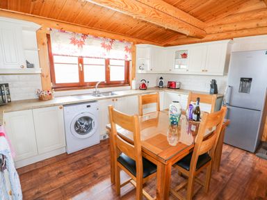 A kitchen with wooden ceiling wooden dining table four chairs washing machine and stainless steel refrigerator at Church View in Greetham Rutland