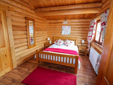 A bedroom with a wooden bed and floral curtains at Church View in Greetham Rutland