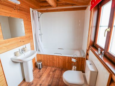 A bathroom with a bathtub shower sink toilet and wooden walls at Church View in Greetham Rutland