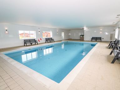 An indoor swimming pool with benches along the walls at Cedar Lodge in Greetham Rutland
