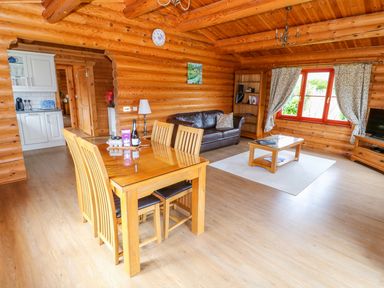 A living and dining area with wooden furniture in a log cabin at Cedar Lodge in Greetham Rutland