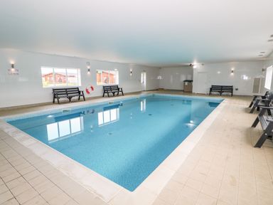 An indoor swimming pool with benches along the walls at Beech Lodge in Greetham Rutland