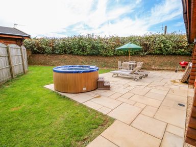 A backyard with a hot tub patio furniture and a barbecue at Beech Lodge in Greetham Rutland